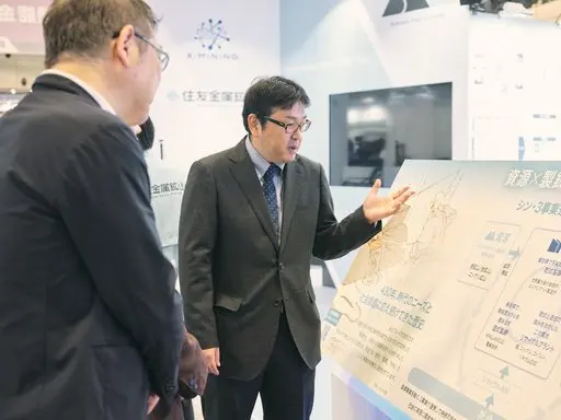 A Sumitomo Metal Mining representative explaining an exhibit panel to visitors at Sustainable Materials Expo 2025