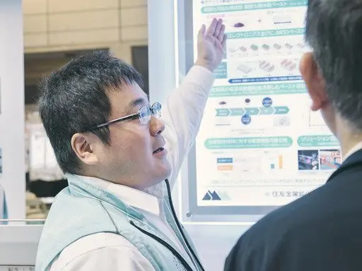 A Sumitomo Metal Mining representative speaking with visitors at the booth
