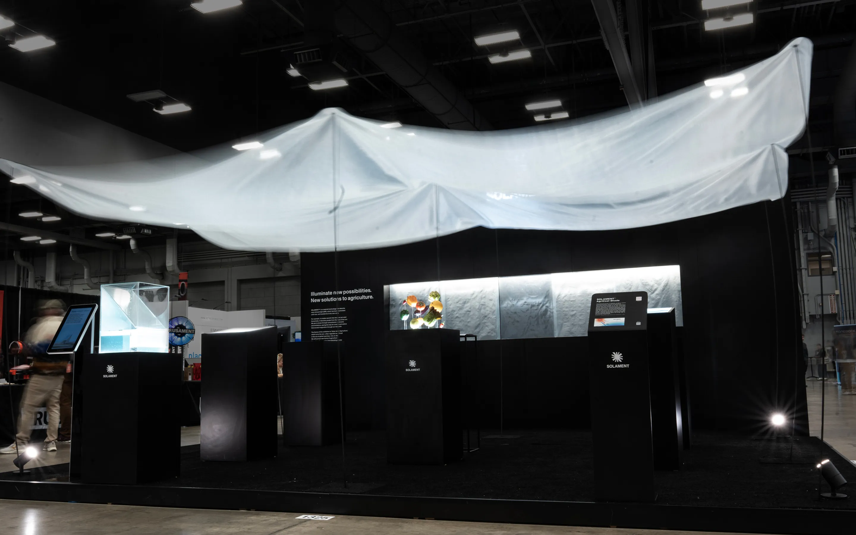 A visual from SXSW 2025. A black SOLAMENT™ booth features a large translucent shade overhead and displays of vegetables and others beneath it