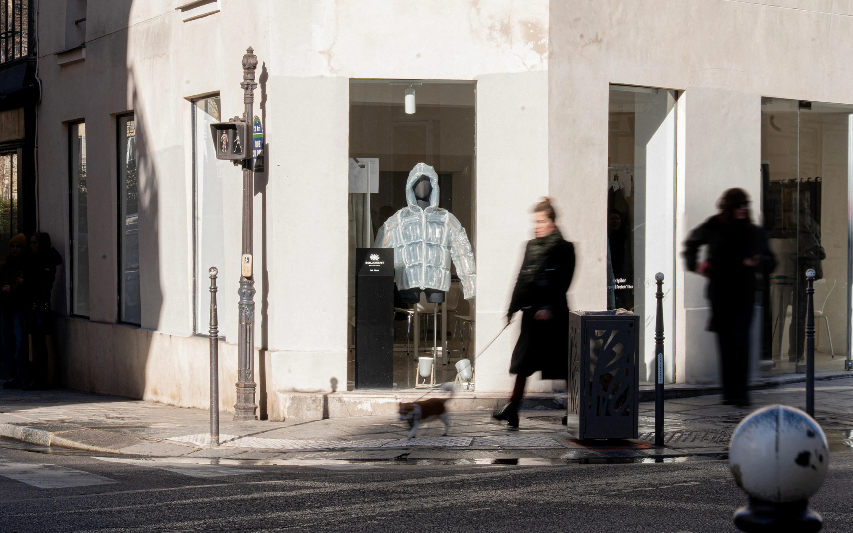 A visual showing the DOWN‑LESS DOWN JACKET displayed in a window at an exhibition in Paris
