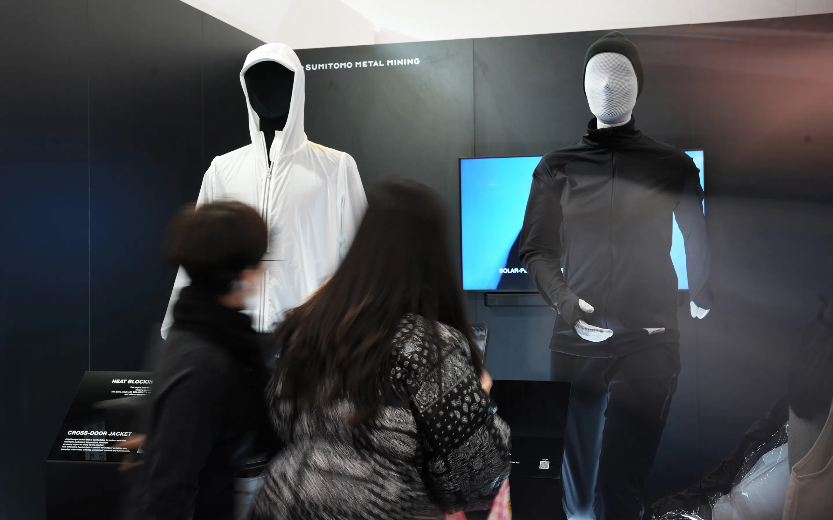 A visual of visitors observing mannequins dressed in the CROSS-DOOR JACKET and SOLAR-PERFORMANCE WEAR at the SOLAMENT™ brand booth at ISPO