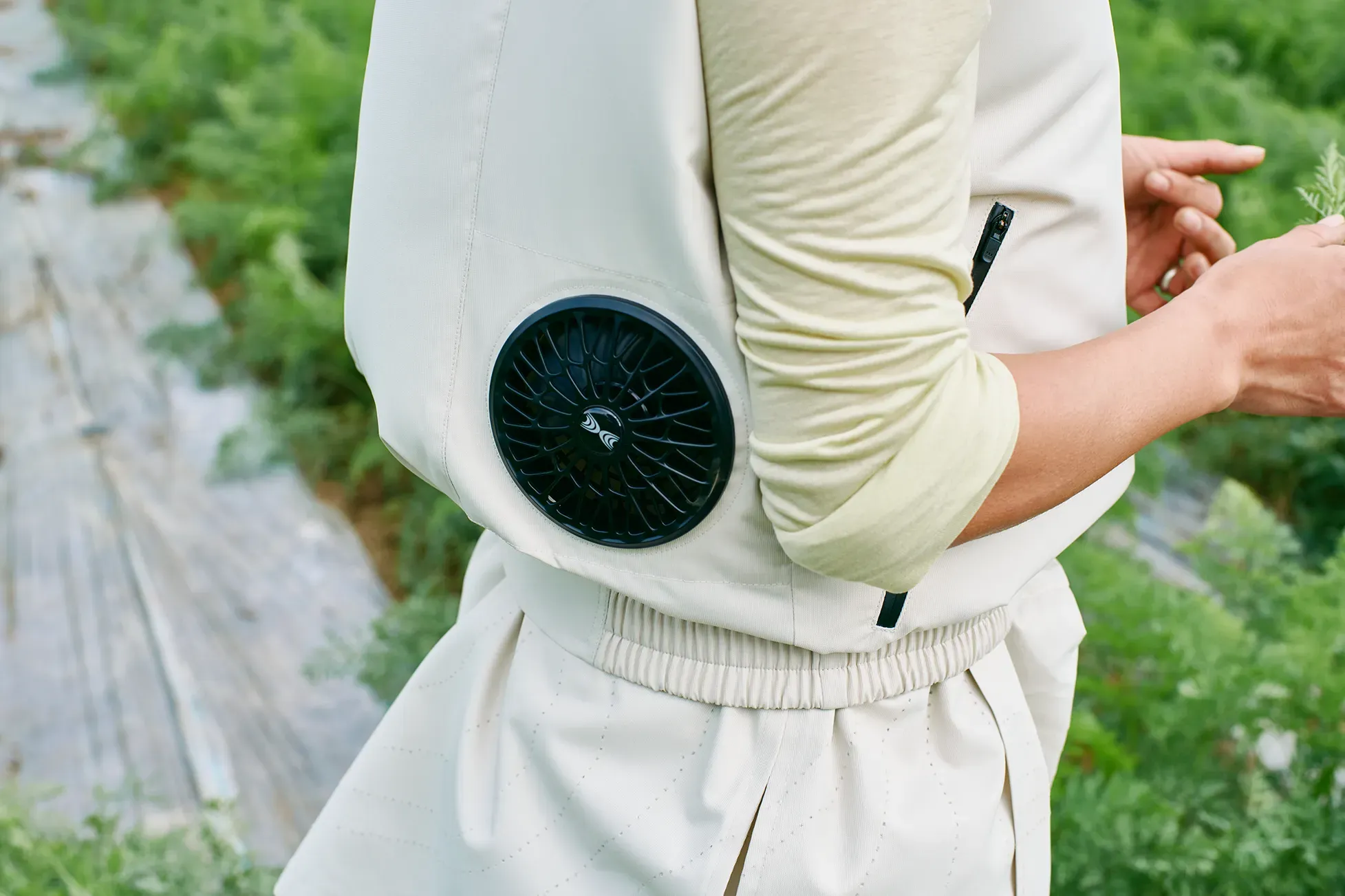 Close-up of the waist of a person wearing a beige fan-equipped HOPE WEAR for Farm Type B vest against farmland.