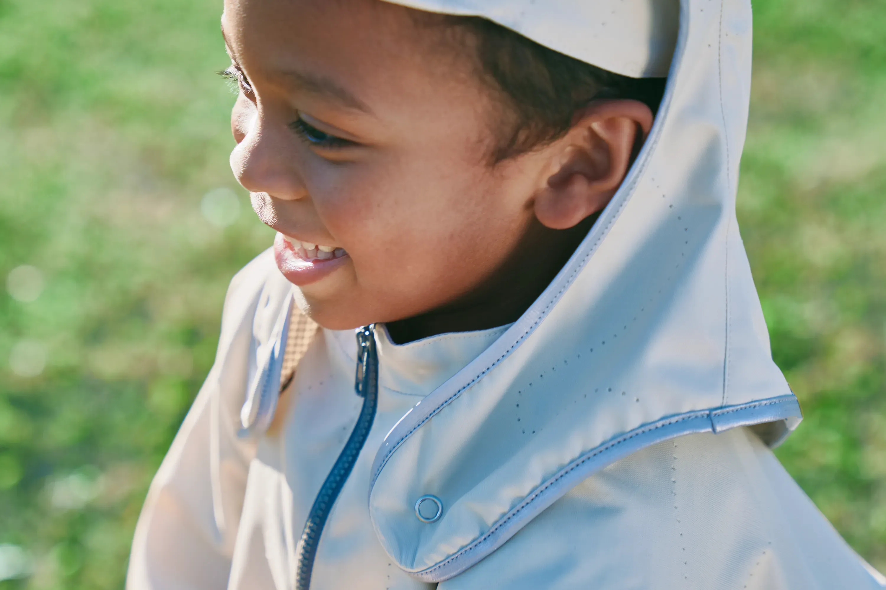 Smiling boy in a sun-shade hat and pleated jacket, HOPE WEAR for Play.