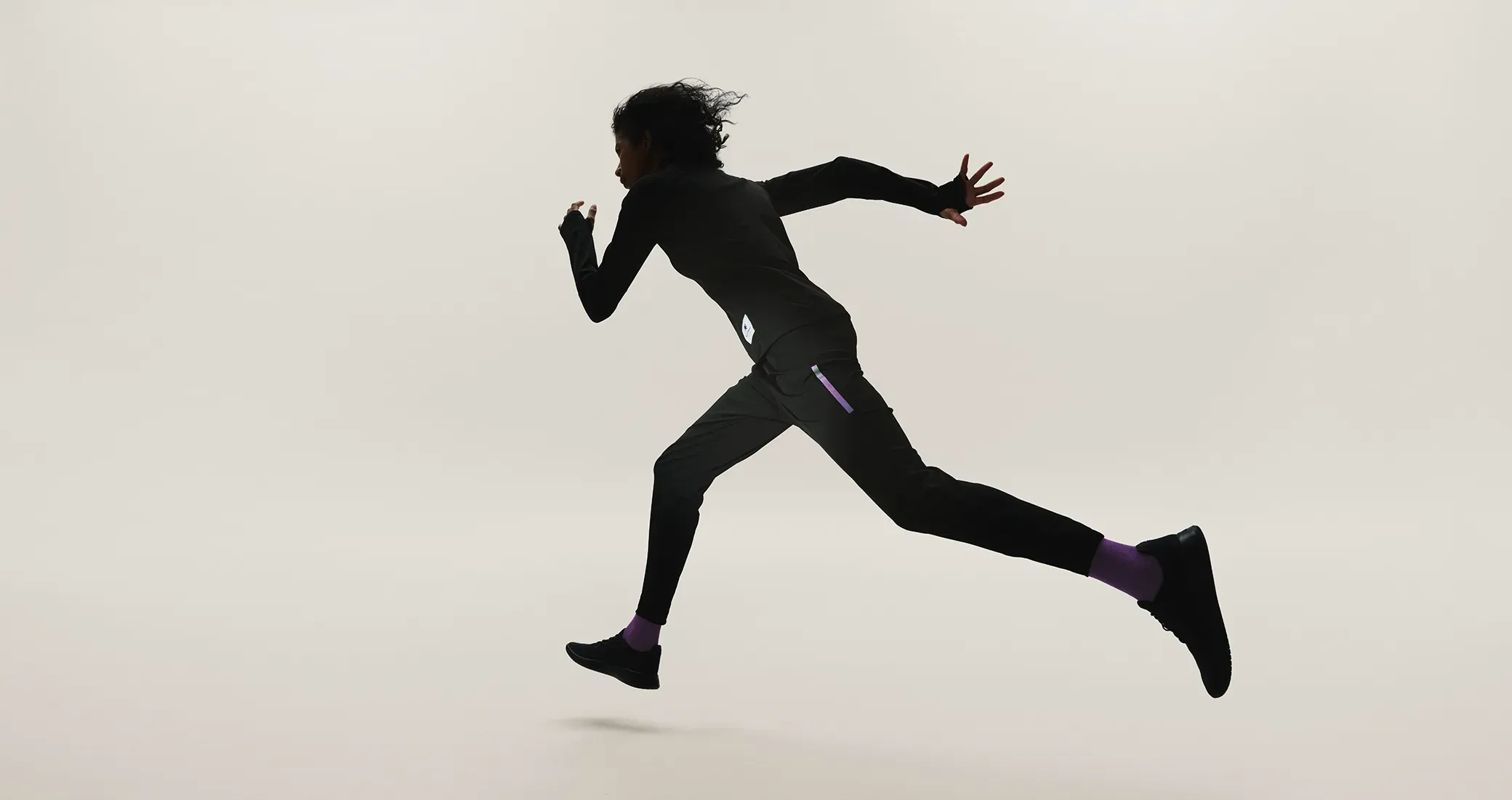 Dynamic running silhouette with purple accents, wearing SOLAR-PERFORMANCE WEAR in cold conditions.